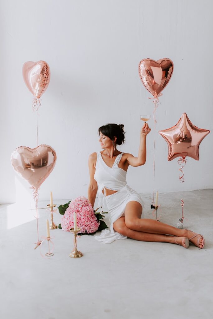 A woman sitting on the floor with balloons and flowers